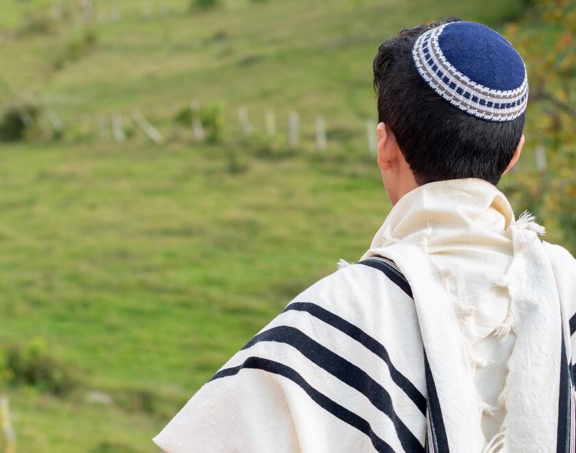 A Jewish teen praying outdoors