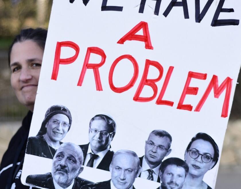 A woman holding a sign with Israel Parliament members photos