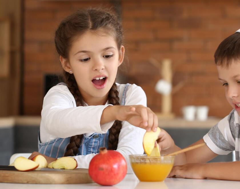 Jewish children eating apples in honey