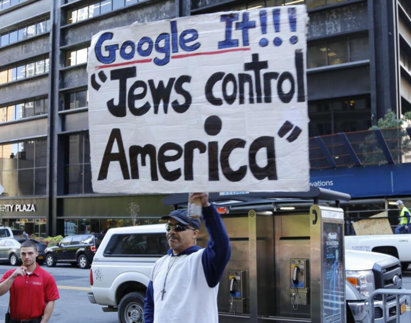 Man holding a sign saying 'Jews control America