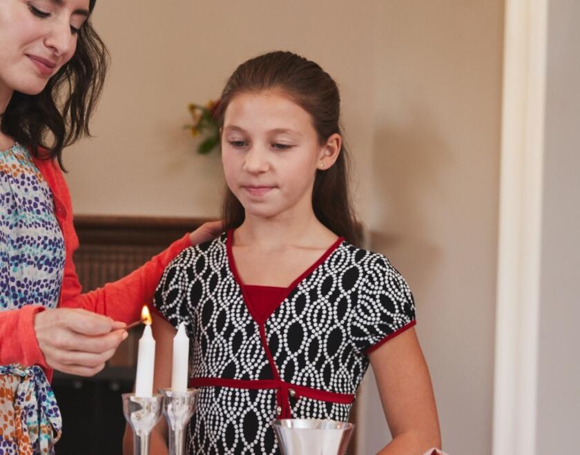 A mother and daughter lighting Shabbat candles