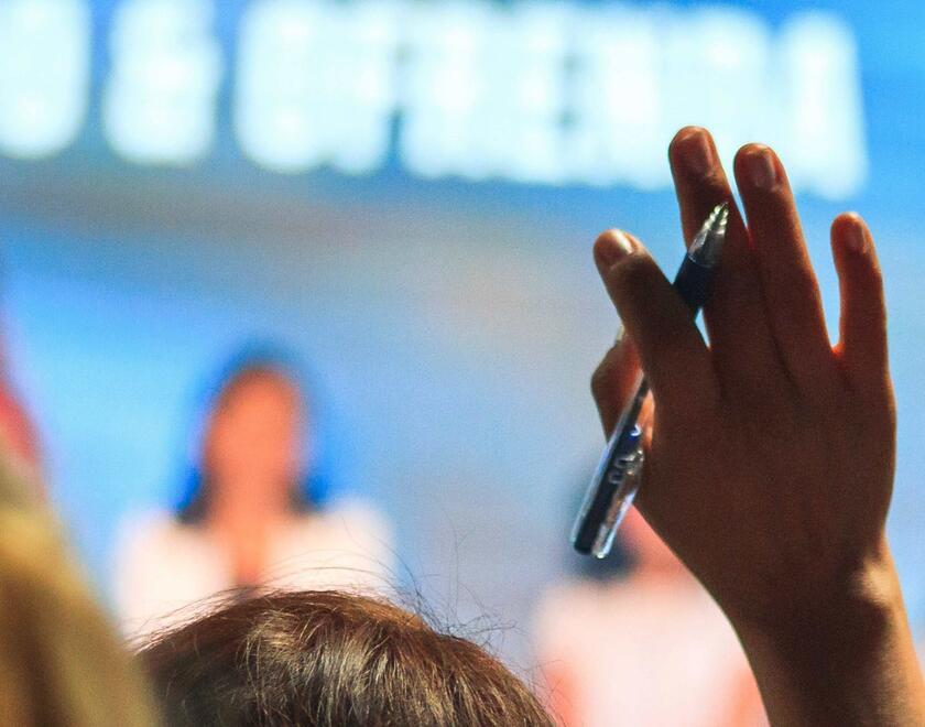 People raising their hands to ask a question