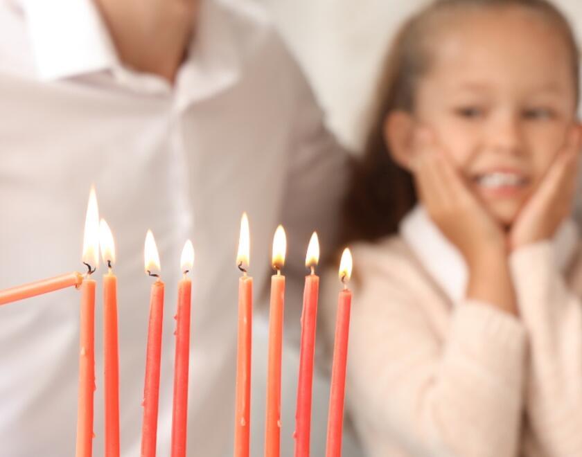 A young family lighting Chanukah candles