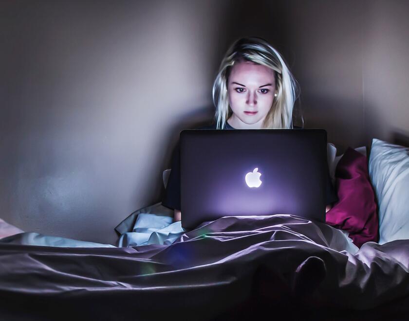 A young woman uses a laptop in the dark